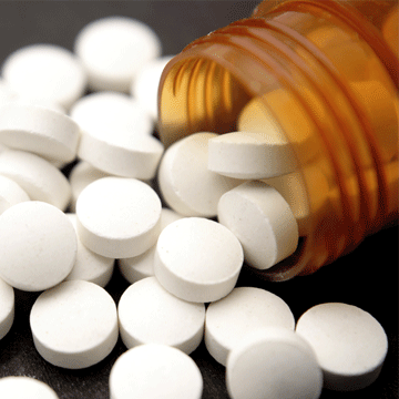 Pills spilling out of an open bottle onto a surface